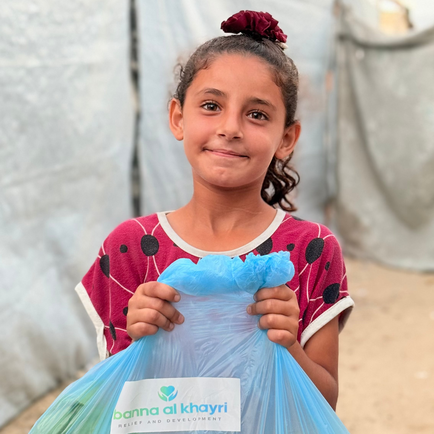 Girl holding a bag of vegetables with 'Al Khayri' branding