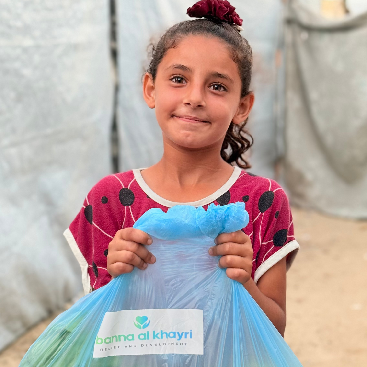 Girl holding a bag of vegetables with 'Banna Al Khayri' branding