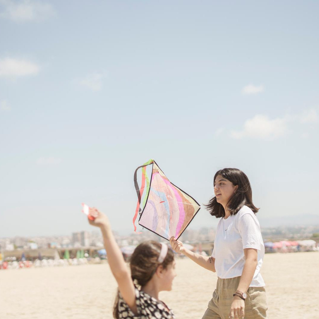 Two people on a beach with a colorful kite