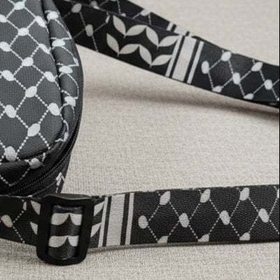 Black and white patterned bag strap on a textured surface